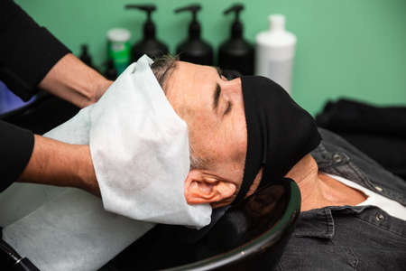 White Caucasian man with black mask of protection pandemic coronavirus is lying down while some...