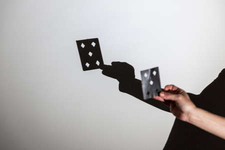 play shadow projected on a white screen. the person's hands shape a card for a magic trick