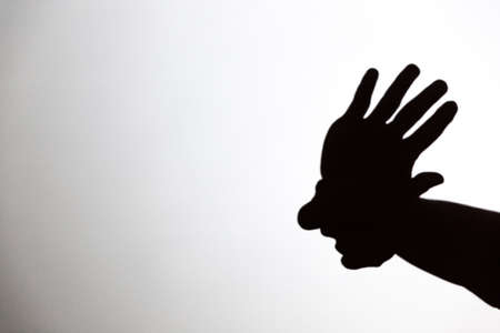 play shadow projected on a white screen. the person's hands form the head of an American Indianの写真素材