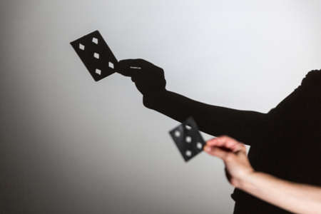 play shadow projected on a white screen. the person's hands shape a card for a magic trick