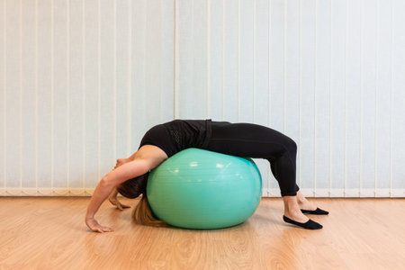 girl pilates trainer does streching bridge fitball posture in fitness centerの写真素材