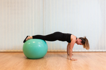 girl pilates trainer does plank fitball basic posture in fitness centerの写真素材