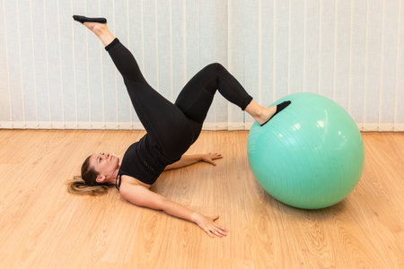 girl pilates trainer does shoulder bridge fitball posture in fitness centerの写真素材