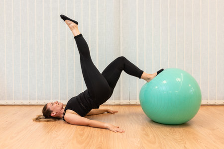girl pilates trainer does shoulder bridge fitball posture in fitness centerの写真素材
