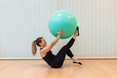 girl pilates trainer does V fitball posture in fitness centerの写真素材