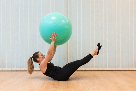 girl pilates trainer does V fitball posture in fitness centerの写真素材