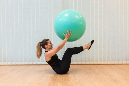 girl pilates trainer does V fitball posture in fitness centerの写真素材