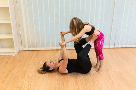 mother yoga and pilates instructor and the daughter perform balance exercisesの写真素材