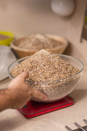 man weighs malt for brewing beer on scaleの写真素材