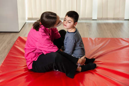 physiotherapy session of disabled child with a physiotherapist, they are huggedの写真素材