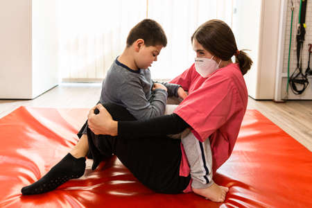 physiotherapy session of disabled child with a physiotherapist, they are huggedの写真素材