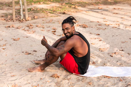 sports guy is sitting on a towel in a park, usually sand. he is african americanの写真素材