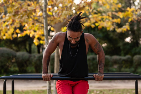 african american athlete boy does calisthenics fitness exercises on bars in parkの写真素材