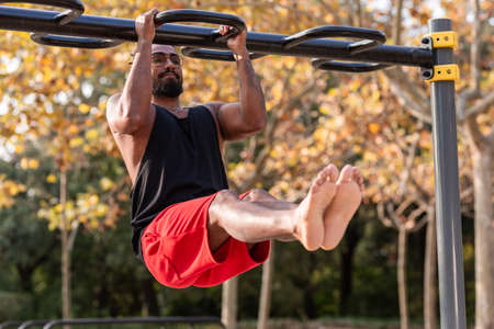 african american athlete boy does calisthenics fitness exercises on bars in parkの写真素材