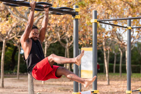 african american athlete boy does calisthenics fitness exercises on bars in parkの写真素材