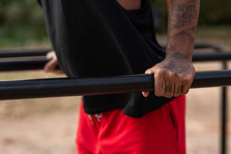 african american athlete boy does calisthenics fitness exercises on bars in park
