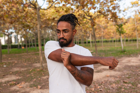 african american guy stretches after a fitness, calisthenics session in a park.