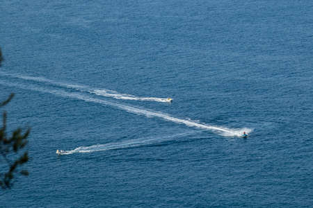 aerial view of two jet skis and a speedboat in the sea with their water wave.の写真素材