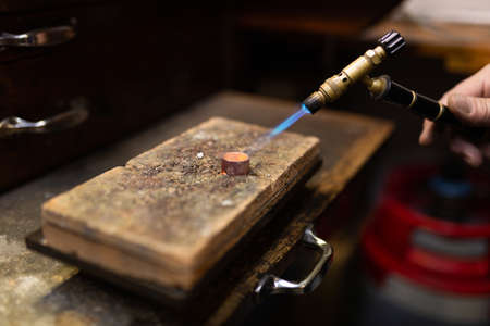 goldsmith jeweler soldering a silver ring on the workbench with a soldering iron and clamping it on...