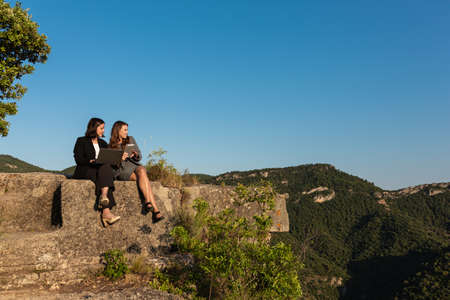 Businesswomen working together with laptop and tablet in mountains