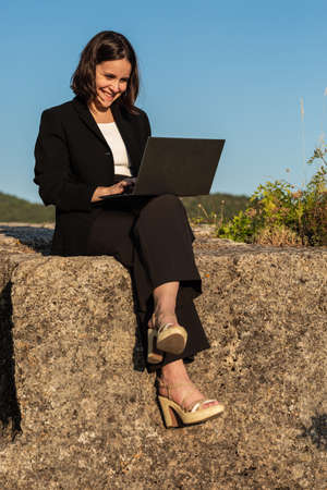 Young woman working on laptop in natureの写真素材