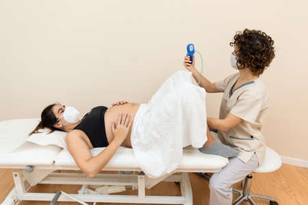 Gynecologist holding a pelvic floor muscle exercise device to prepare for the giving of birth of a woman lyingの写真素材