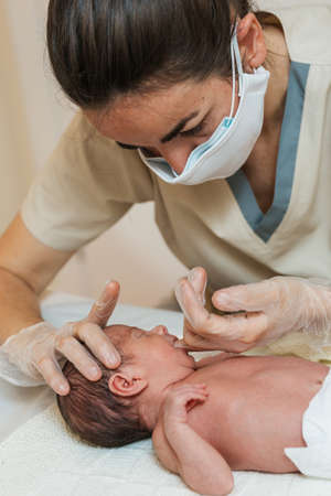 Female physiotherapist performing an evaluation of the maxillary in a newborn baby.の写真素材