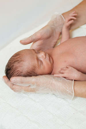 Physiotherapist performing a cervical evaluation on a newborn baby in a medical center.