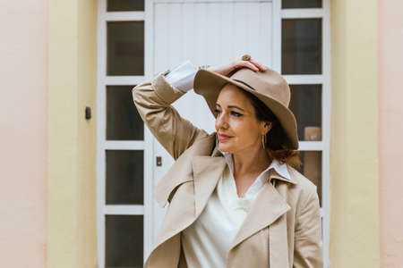 Woman in warm clothes looking away and smiling while standing outdoors on the street.の写真素材