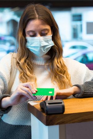 Woman wearing a face mask while paying for beauty treatment at spa reception.の写真素材