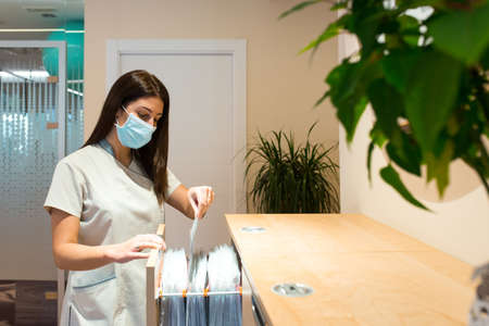 Receptionist of spa center searching files on cabinet