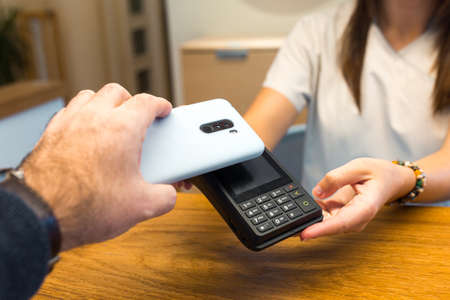 Man using smartphone for payment through terminal