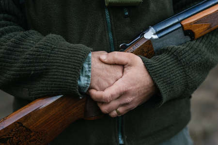 Man in warm clothes standing with rifle in nature