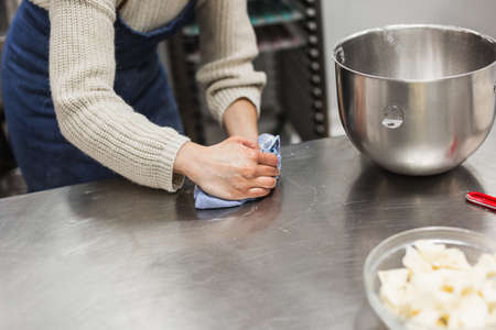 Woman cleaning work table where she is making pastry recipe in bakeryの写真素材