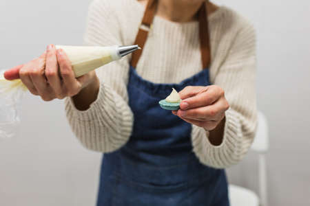 Close up view of a pastry chef filling macaroons with pastry bag while working in the pastry kitchen.の写真素材