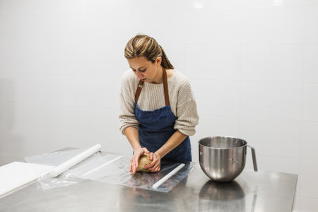 Woman kneading preparation in pastry shop in bakery