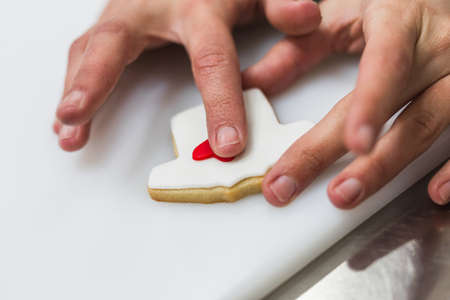 Unrecognizable woman decorating cookies with colored dough