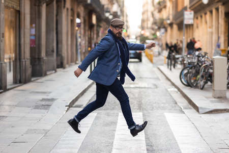 Adult man jumping in pedestrian crossing of street in Barcelonaの写真素材