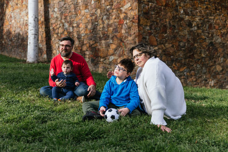 A happy family enjoying a day in the park together sitting on the grassの写真素材
