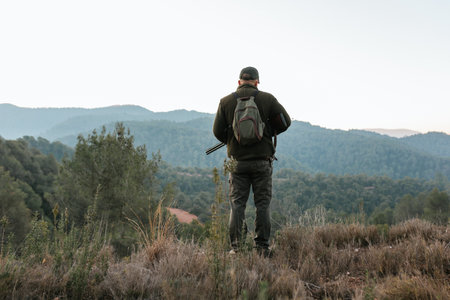Hunter standing on top of mountain range looking downhillの写真素材