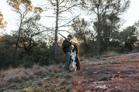 Hunter man and hunting dogs together outdoors in the forest.