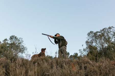 Hunter aiming with his gun in nature