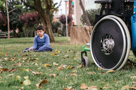 Child with disability sitting on the grass in a park.の写真素材