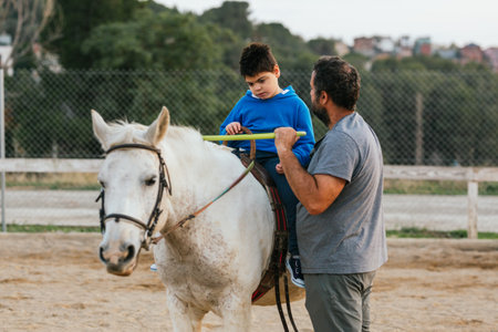 Disabled young man riding a horse assisted by an instructorの写真素材
