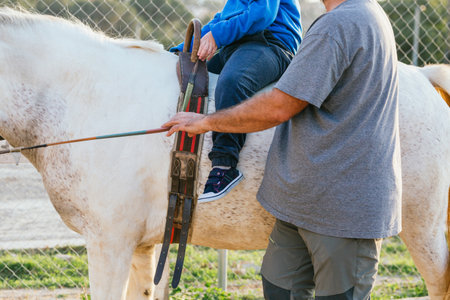 Man leading a horse with a child with disabilities at equine therapy session.の写真素材