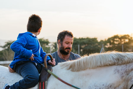 Boy with disabilities enjoying riding a horse outdoors at an equestrian center.の写真素材