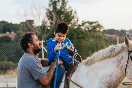 Child with disability doing exercises with the physiotherapist during equine therapy.の写真素材