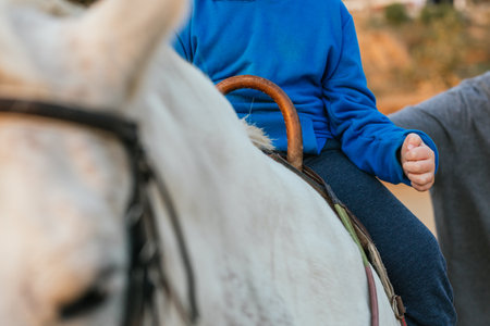 Close up view of a boy riding a horse while having an equine therapy session.の写真素材