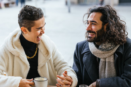Smiling male couple holding hands in a restaurant.の写真素材