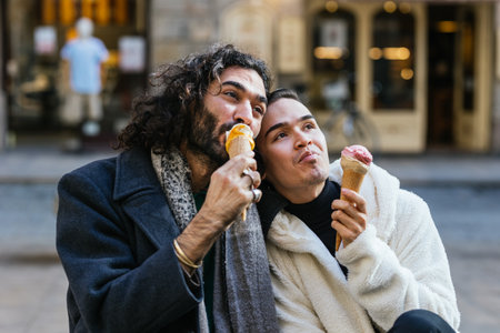 Couple of men sitting in the city eating an ice cream.